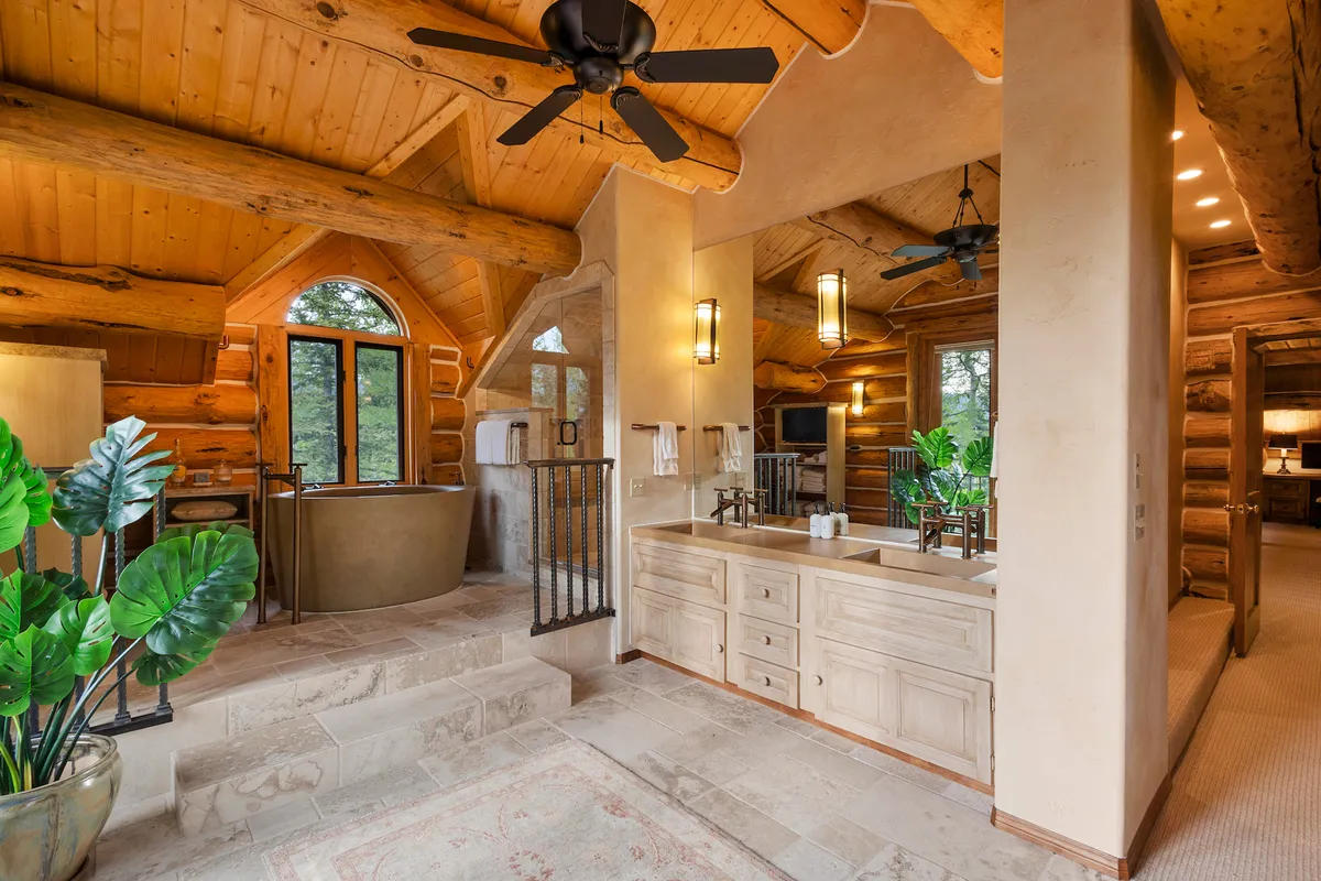 A serene bathroom with a freestanding bathtub, double vanity, large windows letting in natural light, and rustic wooden beams. The atmosphere is tranquil, spa-like, and rejuvenating.